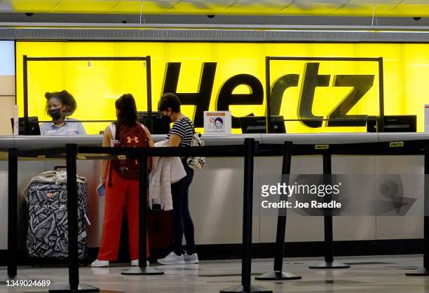 People rent cars at a Hertz car rental counter in the Miami International Airport on October 25, 2021 in Miami, Florida. Hertz announced that it...