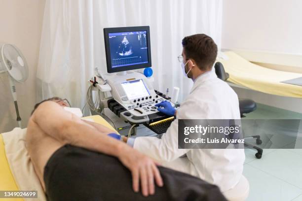 cardiologist doing echocardiogram test of an elderly man - ultrasound scan stock-fotos und bilder