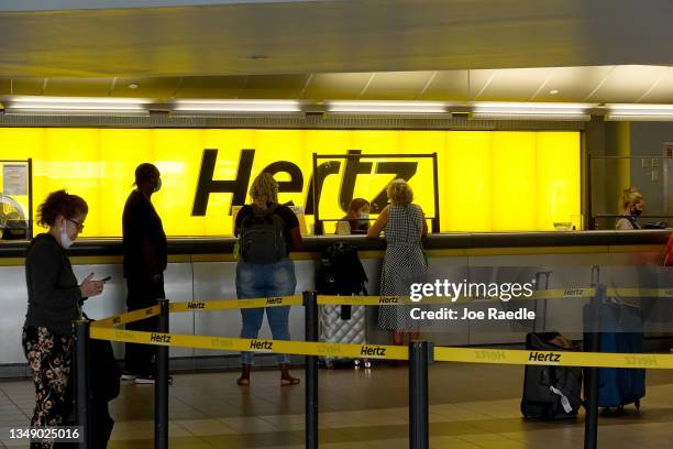 People stand at a Hertz car rental counter in the Fort Lauderdale-Hollywood International Airport on October 25, 2021 in Miami, Florida. Hertz...