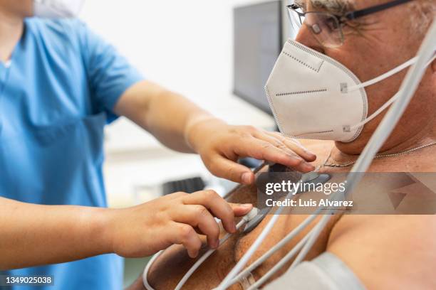 senior man having electrocardiogram test in clinic - cardiopatía fotografías e imágenes de stock