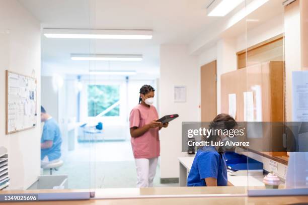 hospital staff working during pandemic at reception - medical administrator stock pictures, royalty-free photos & images