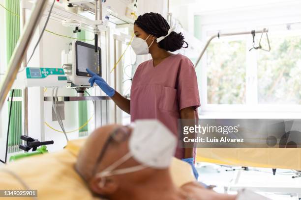 female nurse checking senior patient's vital stats on monitor in the hospital ward - icu ward stock pictures, royalty-free photos & images