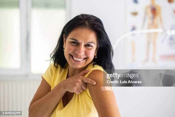 woman happy after getting covid-19 vaccination - vaccine bandage stock pictures, royalty-free photos & images