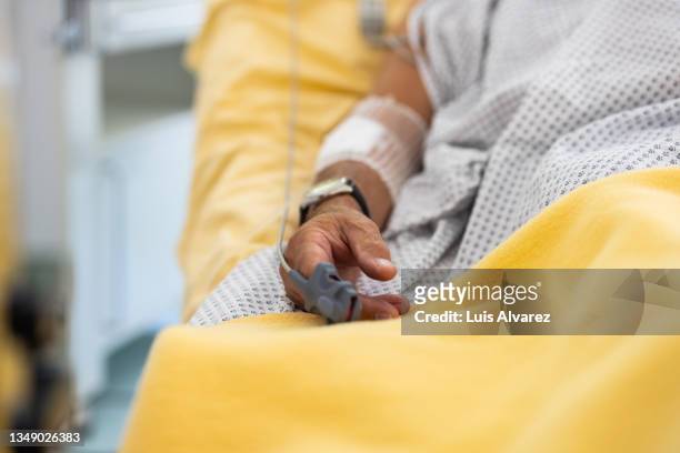 close-up of a male patient's hand in a hospital bed with oximeter - krankenhaus stock-fotos und bilder