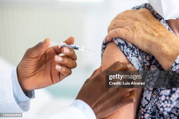 doctor giving coronavirus vaccine to a woman in the medical clinic - antibiotic injection stock pictures, royalty-free photos & images