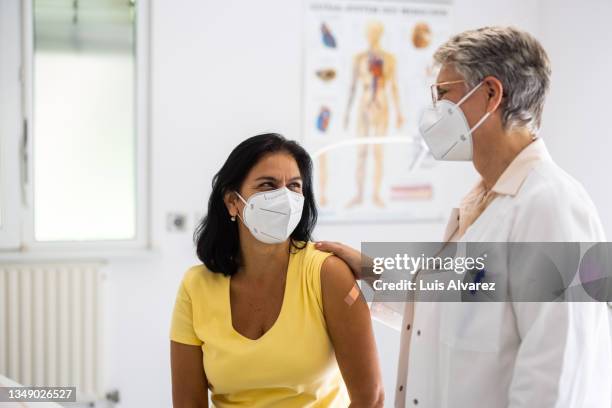 senior doctor talking with female patient in clinic during pandemic - masks fotografías e imágenes de stock