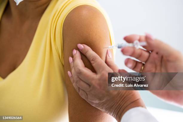 close-up of a doctor giving vaccine to a woman in the medical clinic - injection stock-fotos und bilder