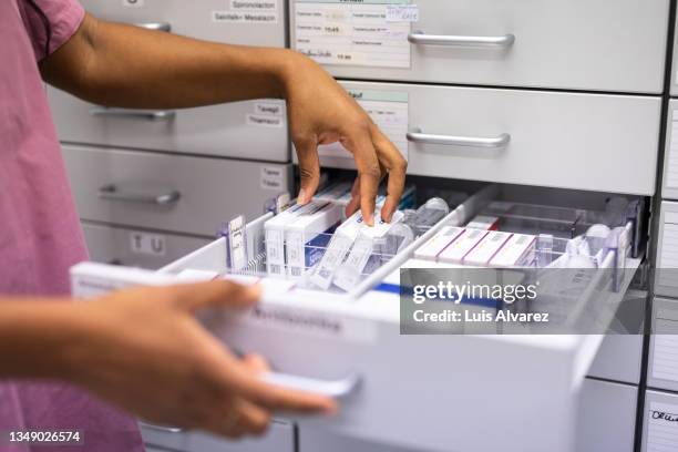 close-up of a female pharmacist searching for prescription medicine in storage rack - drug bust stock pictures, royalty-free photos & images