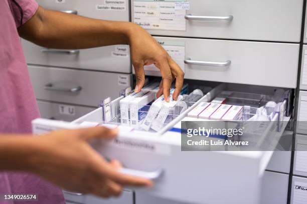 close-up of a female pharmacist searching for prescription medicine in storage rack - sjukvårdsrelaterat material bildbanksfoton och bilder