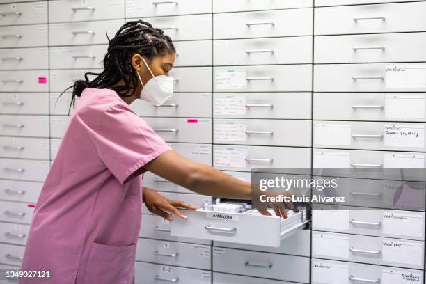 nurse looking for medicine in a storage rack in the hospital pharmacy - pharmacy mask stock pictures, royalty-free photos & images