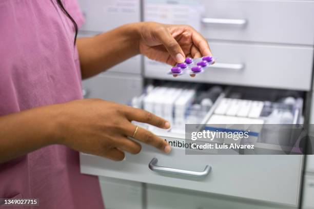 close-up of a woman nurse hands searching for prescription medicine in the storage rack - drug bust stock pictures, royalty-free photos & images