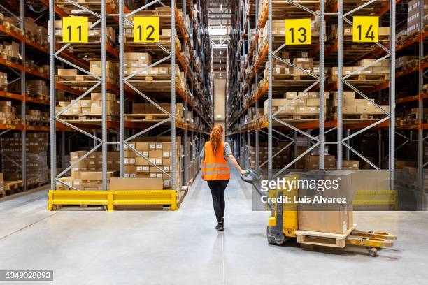 warehouse worker pulling trolley with cardboard boxes - shipping ahead of export figures stock pictures, royalty-free photos & images