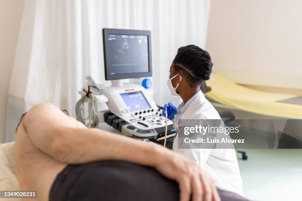 cardiologist performing echocardiography of a senior patient - echokardiogramm stock-fotos und bilder