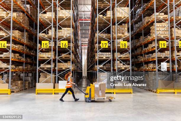 warehouse worker moving boxes on hand truck - warehouse stock-fotos und bilder