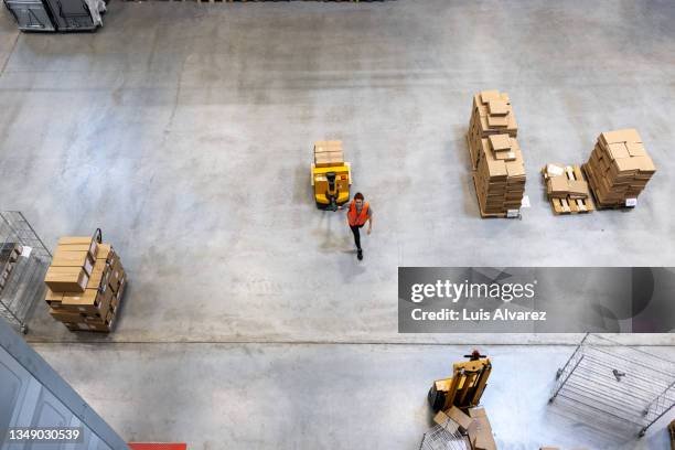 woman warehouse worker moving cargo boxes using pallet jack - fahrzeuge stock-fotos und bilder