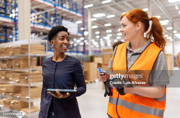 manager walking and talking with a worker in a warehouse - vorarbeiter stock-fotos und bilder