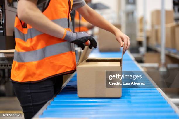 close-up of a female warehouse worker sealing the box on a conveyor belt - packing parcel stockfoto's en -beelden