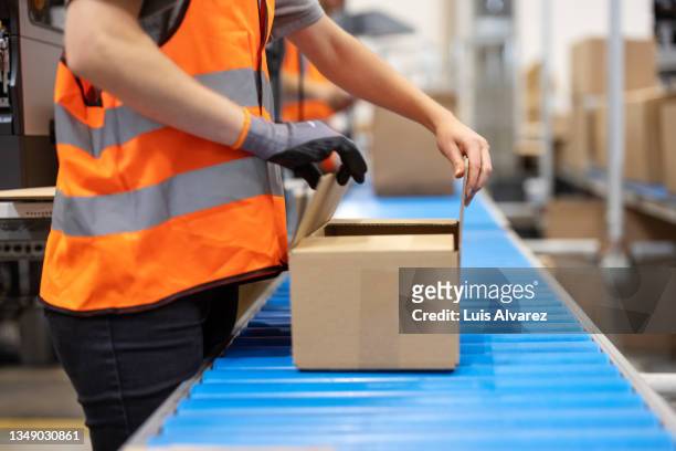 close-up of a female warehouse worker sealing the box on a conveyor belt - caixa de papelão - fotografias e filmes do acervo