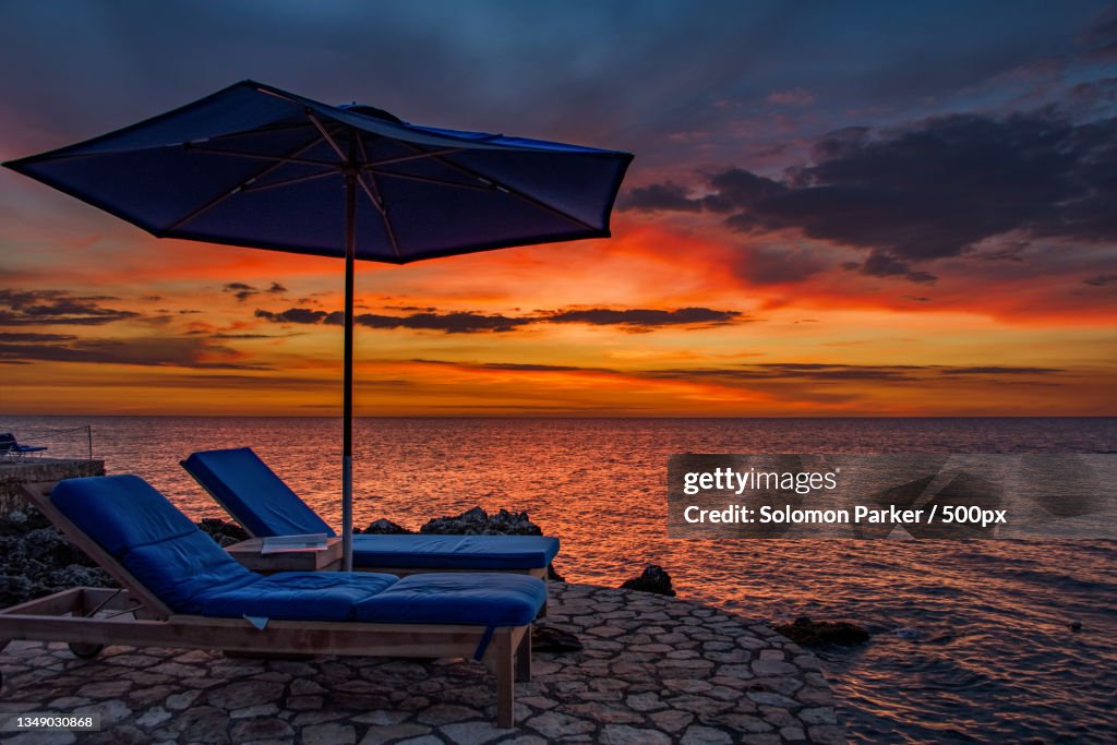 Empty lounge chair on beach against sky during sunset,Negril,Jamaica