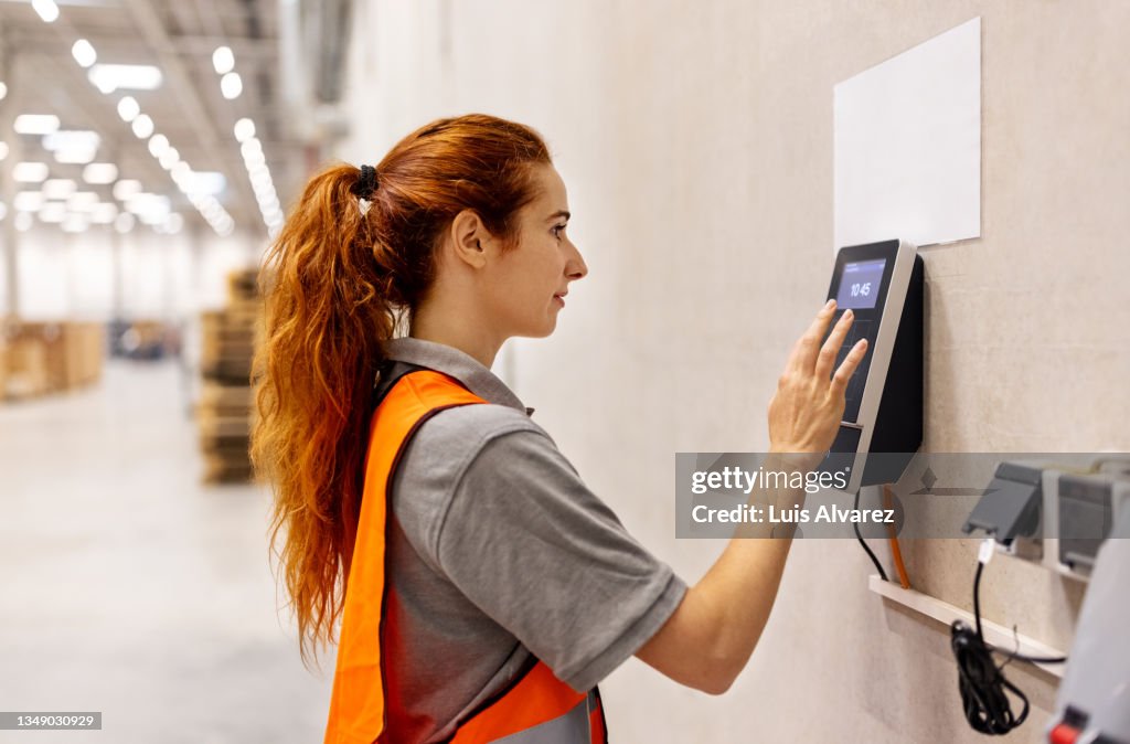 Woman worker uses a biometric machine in warehouse