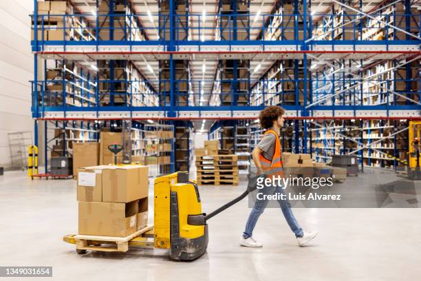 man working in a distribution warehouse moving cargo - pallet jack stock pictures, royalty-free photos & images