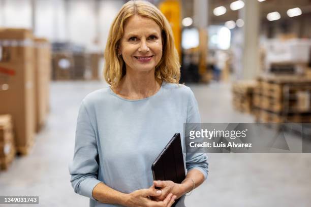 portrait of woman manager with digital tablet standing in warehouse - weibliche führungskraft stock-fotos und bilder