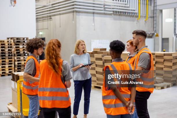 warehouse manager talking with a team of dispatchers in meeting - warehouse worker stock-fotos und bilder