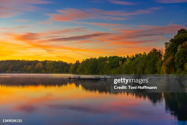 autumn sunrise with reflecting water of the lake wörthsee - lakeshore stockfoto's en -beelden