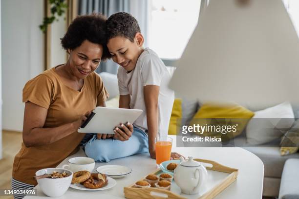 mutter und sohn verbringen morgens zeit miteinander - boy in pajamas and mom on tablet stock-fotos und bilder