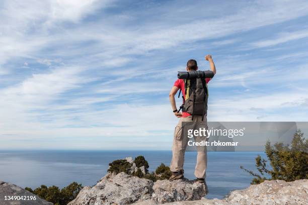successful hiker raised arm at seaside mountain top cliff edge - leadership fist ストックフォトと画像