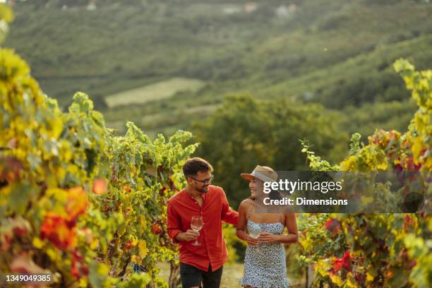 couple enjoying a glass of wine while exploring a vineyard - winery people stock pictures, royalty-free photos & images