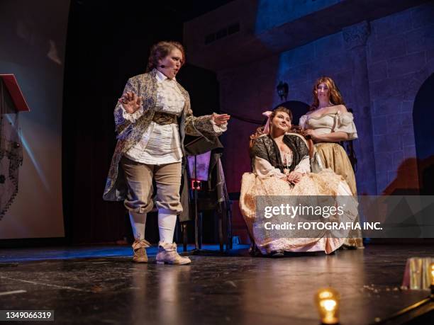 three actresses in period costumes on theatre stage - toneelkostuum stockfoto's en -beelden