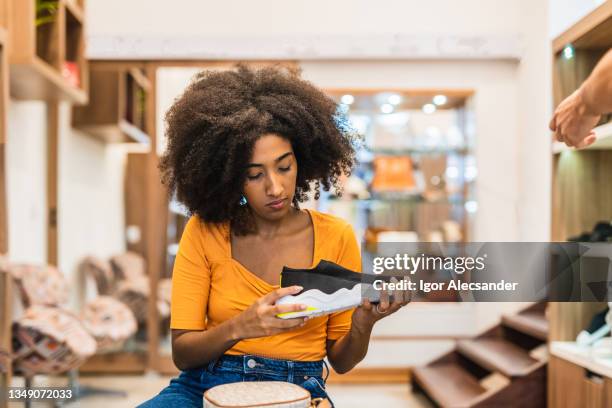 woman looking at running shoes in the store - choosing shoes stock pictures, royalty-free photos & images