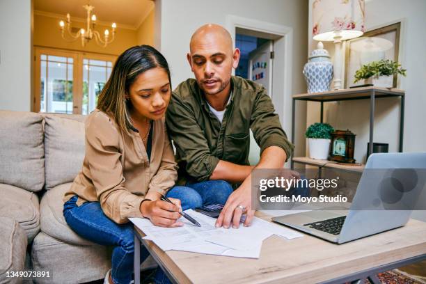 scatto di una giovane coppia che rivede le proprie finanze mentre utilizza il proprio laptop - couple looking laptop foto e immagini stock