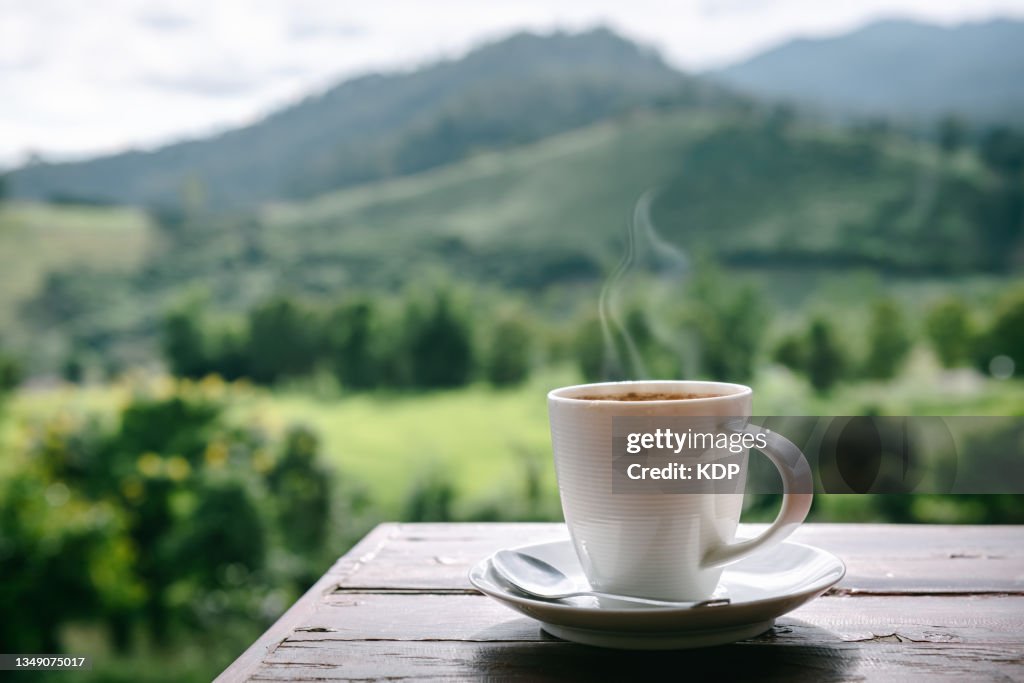 Close-Up of Coffee Cup on Table Against Landscape Scenery Mountain Hill Background.