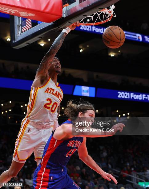 John Collins of the Atlanta Hawks dunks over Kelly Olynyk of the Detroit Pistons during the second half at State Farm Arena on October 25, 2021 in...