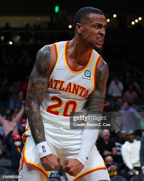 John Collins of the Atlanta Hawks reacts after dunking over Kelly Olynyk of the Detroit Pistons during the second half at State Farm Arena on October...