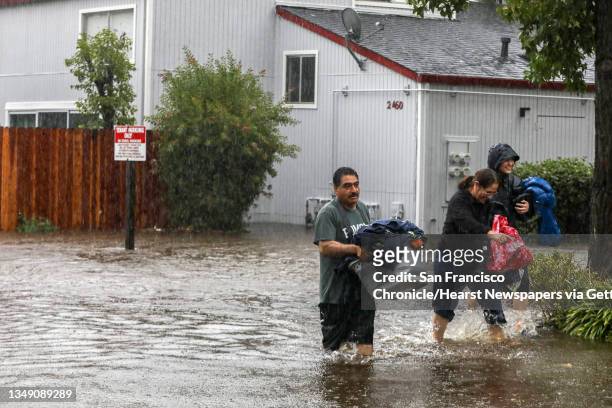 Pablo Paredes, left, and his wife Teresa, center, walk with belongings as they evacuate their home at an apartment building in Santa Rosa, Calif. On...