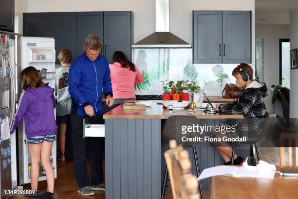 Luke Matthews, 12 does his school work online in the family kitchen in Warkworth (R0 while his sister Jessica Matthews, 10 and dad Charlie prepare...