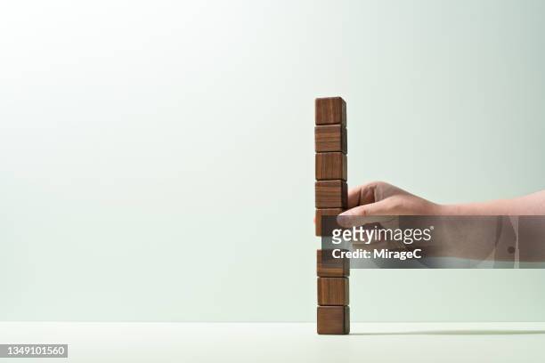 hand separating highly stacked wood blocks - building block copy space stock-fotos und bilder