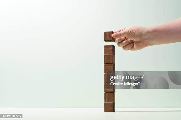 hand add cube to the top of the straight stacked blocks - wood block stacking stock pictures, royalty-free photos & images