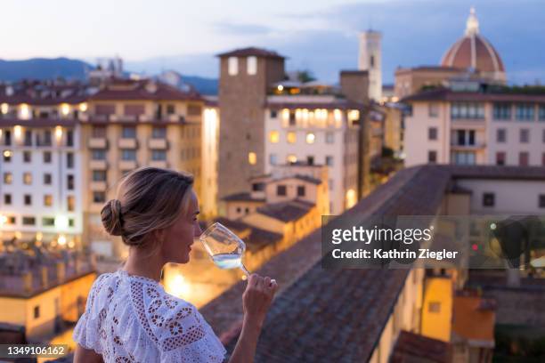 woman in beautiful white dress enjoying a glass of wine with the view of florence - luxury break ストックフォトと画像