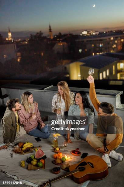 glückliche freunde, die sich während der picknicknacht auf einem dach unterhalten. - night picnic stock-fotos und bilder