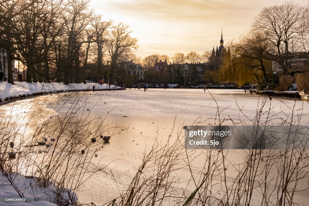 People ice skating on the frozen canals in Zwolle during a beautiful winter day