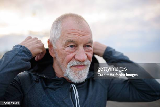 portrait of active senior man resting after doing exercise outdoors on pier by sea in early morning. - senior inhaling stock pictures, royalty-free photos & images