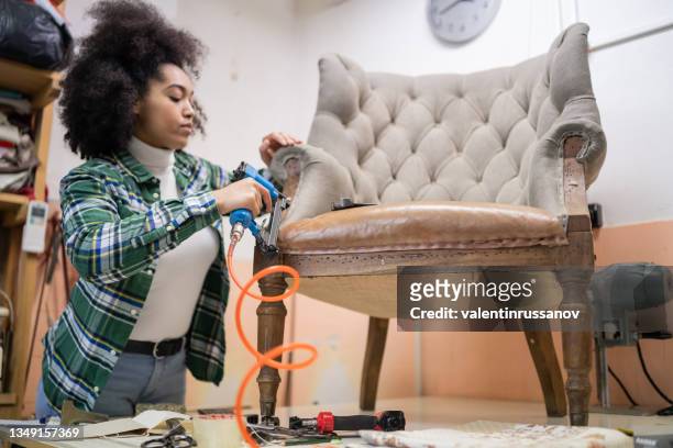 afro female refurbishing chair in upholstery workshop - upholstered furniture stock pictures, royalty-free photos & images