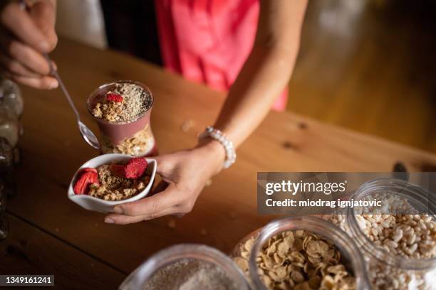 frau fügt müsli mit goji-beeren zu ihrer veganen mahlzeit hinzu - bocksdornfrucht stock-fotos und bilder