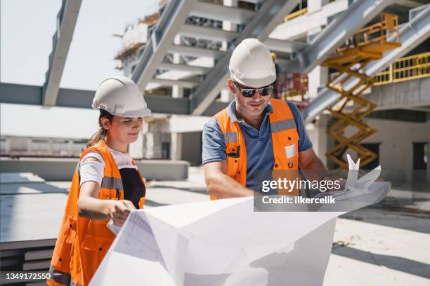 ingeniero civil y arquitecto revisando el proyecto de acuerdo con los planos del plano en el sitio de construcción - ingeniería civil fotografías e imágenes de stock