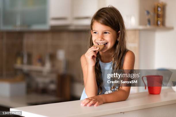 porträt eines schönen mädchens, das kekse isst - eating cookies stock-fotos und bilder