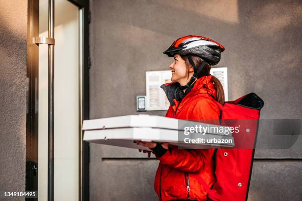 woman delivering pizza at residential building - take away food courier stock pictures, royalty-free photos & images